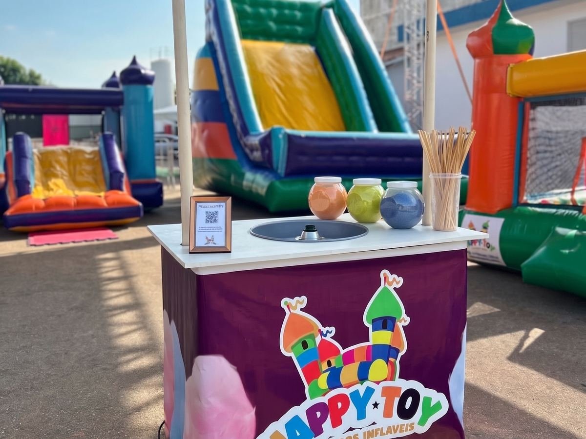 Barraca de algodão doce da Happy Toy montada em um evento, com açúcar colorido e palitos